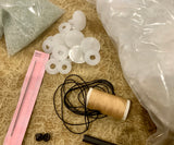 The kit includes , mohair with the pattern drawn out ready for cutting out, DMC black perle thread with a darning/ doll maker’s needle for embroidering the nose and mouth and inserting the eyes, plastic joints, polyester stuffing, glass beads and extra strong thread. A small sketchers soft water soluble pencil.