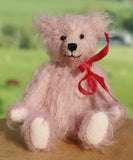 Teddy bear with a red ribbon on a wooden surface with a blurred green background