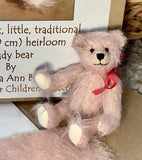 Stuffed teddy bear with a red bow in front of its Make A Teddy kit box