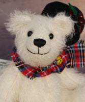 Theo's head with his hat off to show you his face.
Theo sitting and waving. The Christmas Teddy bear sewing kit makes Theo who is a 6.5”/ 17cm (approx) fully jointed, white mohair (12mm sparse) bear wearing a black felt hat with felt holly leaves, red glass berry beads and a star sequin plus a tartan scarf with a yellow glass bead. He has black glass eyes , a cute little tail and a black embroidered nose. He is quite heavy and squidgy and very smiley.