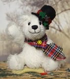 Theo sitting and waving. The Christmas Teddy bear sewing kit makes Theo who is a 6.5”/ 17cm (approx) fully jointed, white mohair (12mm sparse) bear wearing a black felt hat with felt holly leaves, red glass berry beads and a star sequin plus a tartan scarf with a yellow glass bead. He has black glass eyes , a cute little tail and a black embroidered nose. He is quite heavy and squidgy and very smiley.