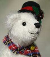 Side view of Theo's head to show you his big smile.
Theo sitting and waving. The Christmas Teddy bear sewing kit makes Theo who is a 6.5”/ 17cm (approx) fully jointed, white mohair (12mm sparse) bear wearing a black felt hat with felt holly leaves, red glass berry beads and a star sequin plus a tartan scarf with a yellow glass bead. He has black glass eyes , a cute little tail and a black embroidered nose. He is quite heavy and squidgy and very smiley.